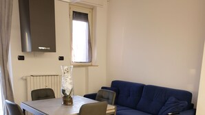 Ein Essbereich mit Tisch, Stühlen, einem blauen Sofa und einem Fenster mit Vorhängen.