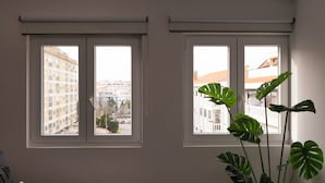 A room with two windows, a sofa, and a potted plant. - Snuggly Corner by Trip2Portugal (Figueira da Foz)