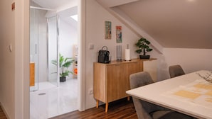 A modern room with a wooden cabinet, a dining table, and chairs. There is a potted plant on the cabinet and a small table with a vase. - Snuggly Corner by Trip2Portugal (Figueira da Foz)