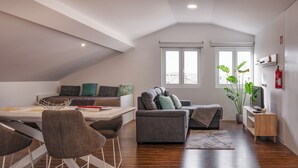 A modern loft apartment with a dining area, seating, and a large window. - Snuggly Corner by Trip2Portugal (Figueira da Foz)