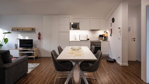 A modern living room with a sofa, TV, and dining table with chairs. - Snuggly Corner by Trip2Portugal (Figueira da Foz)