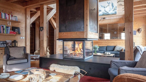 A cozy cabin interior with a fireplace, wooden beams, a sofa, and a dining table. - Chalet Uska - Enjoy the thrill of the Alps all year round - OVO Network (Combloux)