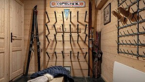 A ski storage room with wooden walls, a sign reading "COMBLOX", and multiple ski racks. - Chalet Uska - Enjoy the thrill of the Alps all year round - OVO Network (Combloux)