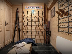 Un depósito para esquíes con paredes de madera, un letrero que dice "COMBLOX" y varios portaesquíes.