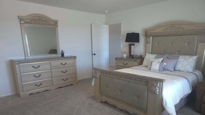 Een slaapkamer met een groot bed, een kaptafel, een spiegel en een nachtkastje.