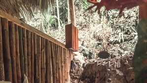 Zona de baño de piedra con pared de madera y valla de bambú.