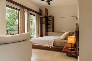 A bedroom with a bed, a nightstand, a lamp, a wooden shelf, and a window with curtains.