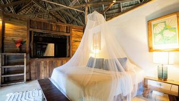 Quarto com cama sob dossel, paredes de madeira, um banco, uma luminária e um quadro na parede.