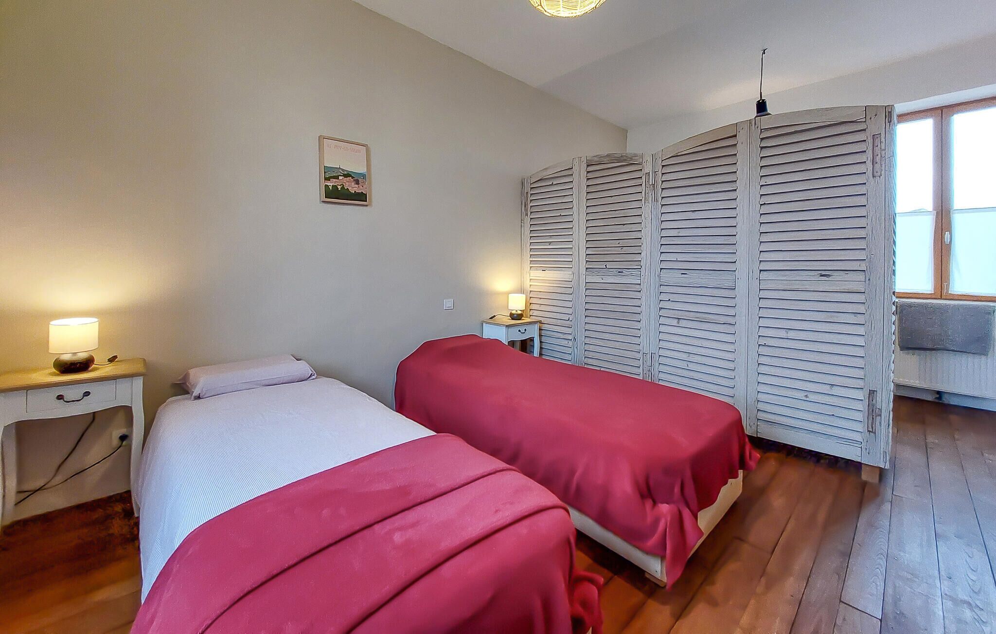 Une chambre avec deux lits, une table de chevet avec une lampe, une armoire en bois et une petite table avec une lampe.