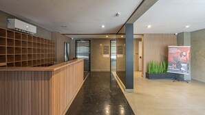 A modern lobby with a reception desk, elevators, and a promotional stand. - Studio 407 Perdizes 900m Allianz Parque c Academia (São Paulo)
