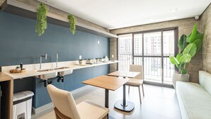 A modern kitchen with a built-in sink, a countertop with plants, and a window overlooking a cityscape. - Studio 407 Perdizes 900m Allianz Parque c Academia (São Paulo)