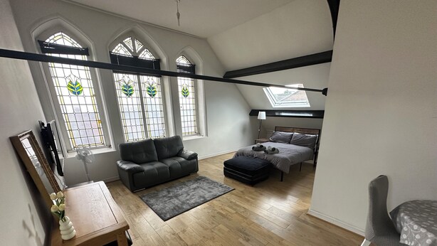 Ein geräumiges Schlafzimmer im Loft-Stil mit einem großen Bett, einer Schlafcouch und einem Schreibtisch.