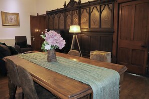 A wooden dining table with a green table runner, a vase with pink flowers, and a floor lamp. - Luxury Converted Church (Droylsden)