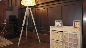 Ein Zimmer mit einem Stativ-Stehlicht, einem Fernseher und einem Korbspeicher mit gerahmten Kunstwerken.