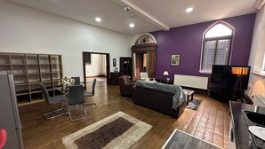 Ein Wohnzimmer mit einer Couch, Sesseln, einem Fernseher und einem Bücherregal.