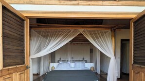 Uma cama com dossel, paredes de madeira e uma porta visível.