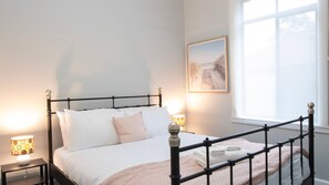 A neatly made bed with a headboard, a bedside lamp, and a framed picture on the wall.