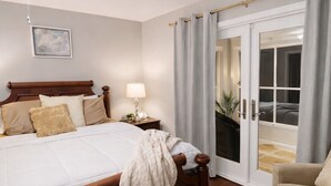 Ein Schlafzimmer mit Bett, Nachttischlampe und Blick durch eine Glastür.