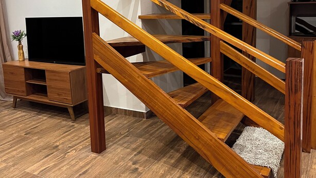 Un escalier en bois, un meuble pour télévision et une petite table dans un salon moderne.