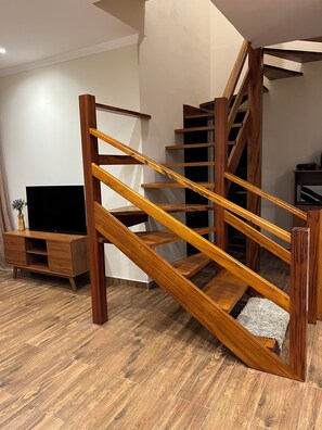 Una escalera de madera con un mueble para televisión y una mesita en una sala de estar moderna.
