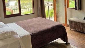 Une chambre à coucher avec un lit, une grande fenêtre, un balcon et une porte-fenêtre coulissante.