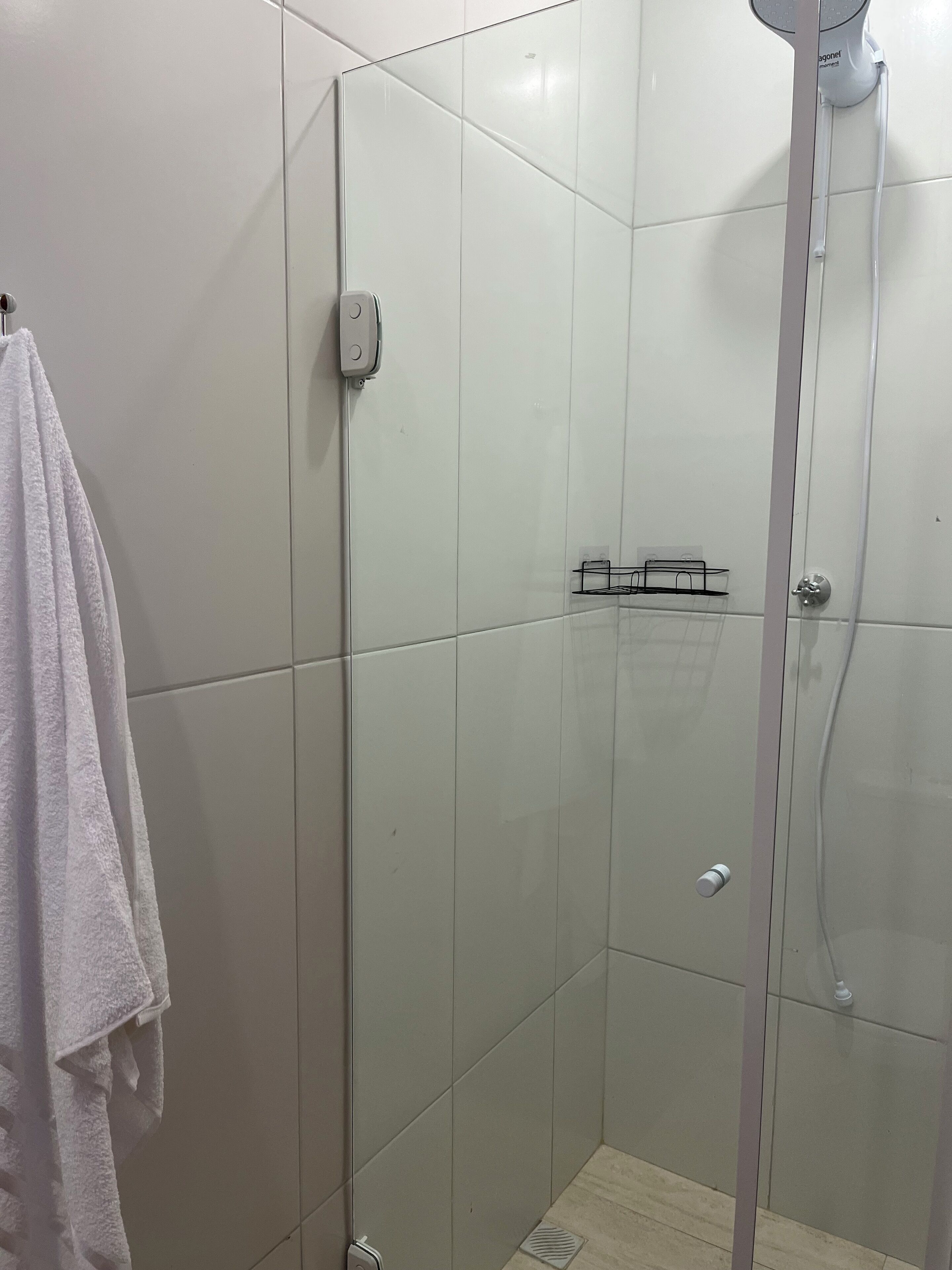 A glass-enclosed shower stall with a towel rack to the left.