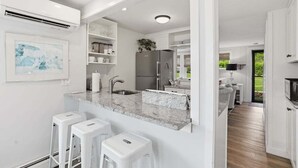 Une cuisine moderne avec des meubles blancs, un plan de travail en marbre et un réfrigérateur en acier inoxydable.
