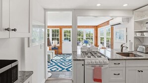 Une cuisine moderne avec des armoires blanches, une cuisinière à gaz et une grande fenêtre.