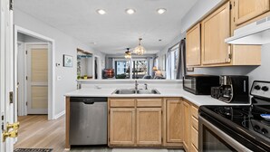 Una cocina moderna con armarios de madera, lavavajillas, estufa y microondas.