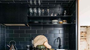 Une cuisine moderne avec des carreaux de couleur sombre, un plan de travail en bois et un four encastré.