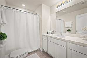 Ein modernes Badezimmer mit Duschvorhang, Waschbecken, Spiegel und Toilette.
