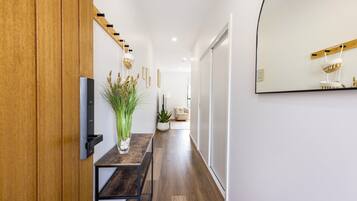 A hallway with a wooden door, a table with a vase, a plant, and a mirror on the wall.