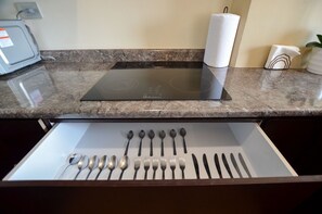 A kitchen with a built-in induction cooktop, a paper towel holder, and a drawer with neatly arranged utensils. - ¡A pasos de Barrio Antiguo! Cama King + Parking (Monterrey)
