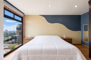 A bedroom with a large bed, a nightstand, a dresser, and a view of a cityscape through a large window. - ¡A pasos de Barrio Antiguo! Cama King + Parking (Monterrey)