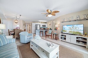 A living room with a TV, sofa, and dining area. - Tradewinds 306 | Indoor, Outdoor Pools | Beachfront | My Beach Getaways (Orange Beach)