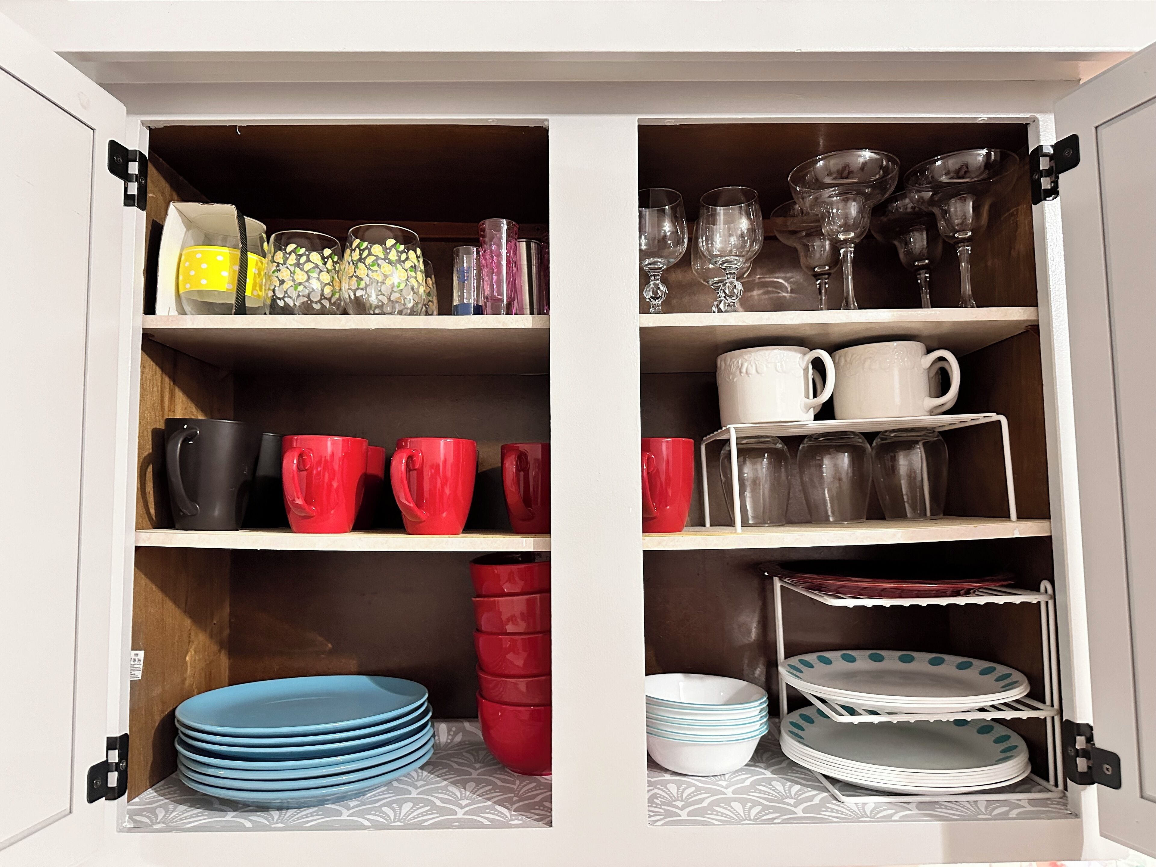 A cabinet with shelves containing various kitchenware, including mugs, plates, and glassware.
