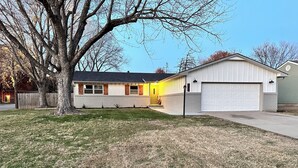 A single-story house with a garage, a front yard with a tree, and a clear sky. - Kechi Kottage- Sept. special- 20% off 2+ ni stay! Ask host. Pet friendly. Safe! (Kechi)