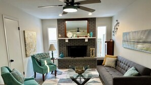 A living room with a fireplace, two green armchairs, a sofa, and a glass coffee table. - Kechi Kottage- Sept. special- 20% off 2+ ni stay! Ask host. Pet friendly. Safe! (Kechi)