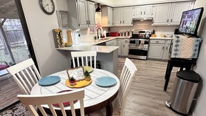 A modern kitchen with white cabinets, a central island, and a dining area with white chairs. - Kechi Kottage- Sept. special- 20% off 2+ ni stay! Ask host. Pet friendly. Safe! (Kechi)