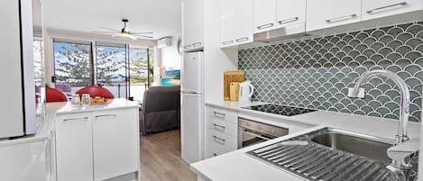 A modern kitchen with white cabinets, a stainless steel sink, and a patterned backsplash.