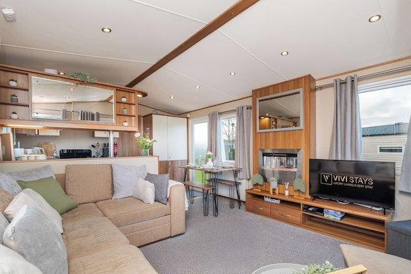 A modern RV interior with a sofa, TV, dining area, and kitchen.