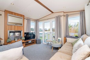 A modern living room with a television, sofa, and a large window with curtains.