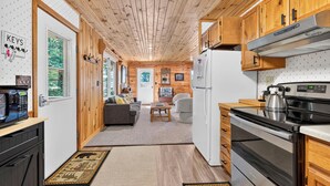 A compact kitchen with wooden cabinets, a stainless steel stove, and a refrigerator. - Cozy Pines on Diamond Lake (Cable)