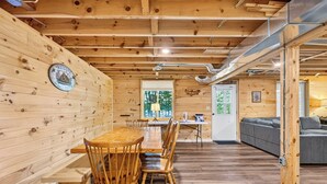 A wooden interior with a dining area, a sofa, and a window with a view. - Cozy Pines on Diamond Lake (Cable)