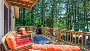 A wooden deck with wicker furniture and a grill, surrounded by a forest. - Cozy Pines on Diamond Lake (Cable)