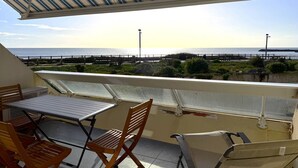 Ein Balkon mit Meerblick, einem Tisch und zwei Stühlen.