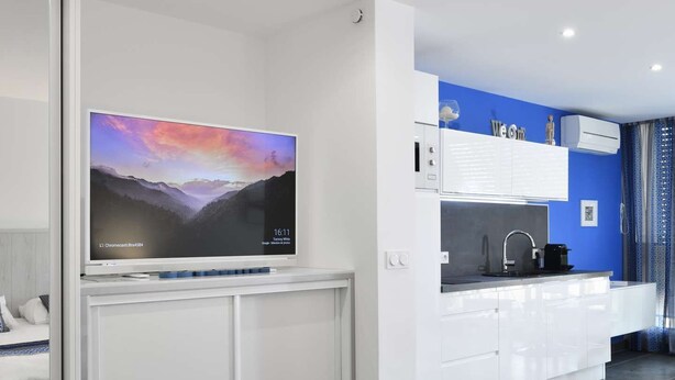 Ein modernes Hotelzimmer mit einem großen Bett, einem Flachbildfernseher, einer Küchenzeile und einem Badezimmer.