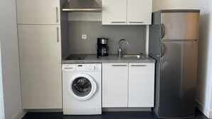 Una cocina compacta con lavadora, cafetera y refrigerador.