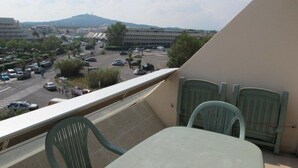 A balcony with a table and chairs, overlooking a parking lot and buildings. - Studio Héliopolis E 20 - 2 people (AGDE)