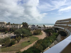 Un hôtel doté d’un bâtiment aux lignes courbes, d’un parking et offrant une vue sur la mer.